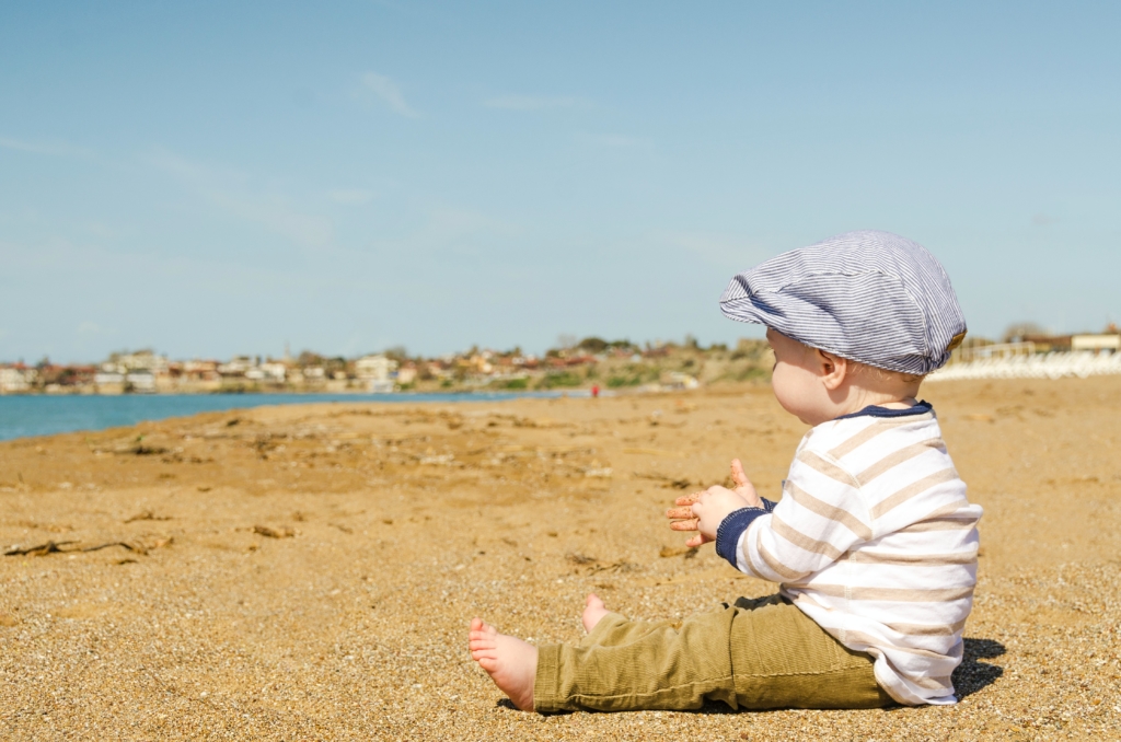 Un enfant habillé en petit homme est assis sur la plage